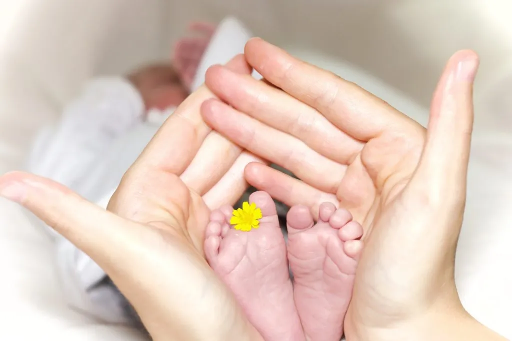 A newborn's feet held in a parent's hands