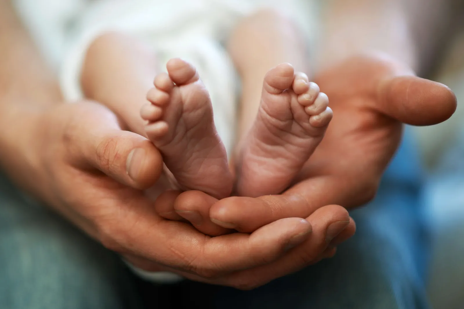 A newborn's feet held in a parent's hands